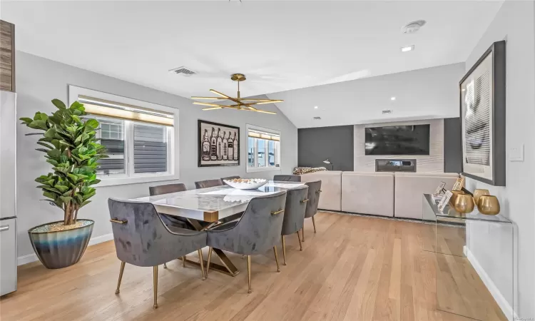 Dining area with an inviting chandelier, light wood-type flooring, and vaulted ceiling