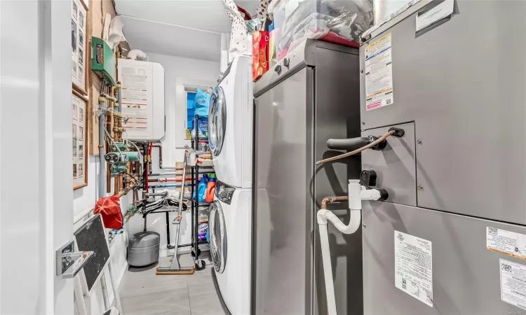 Utility room featuring stacked washer / dryer and water heater