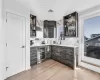 Bar featuring sink, beverage cooler, tasteful backsplash, light hardwood / wood-style flooring, and dark brown cabinets