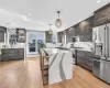 Kitchen with sink, light hardwood / wood-style floors, decorative light fixtures, a kitchen island, and high end appliances