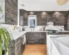 Kitchen featuring exhaust hood, sink, light wood-type flooring, appliances with stainless steel finishes, and dark brown cabinetry