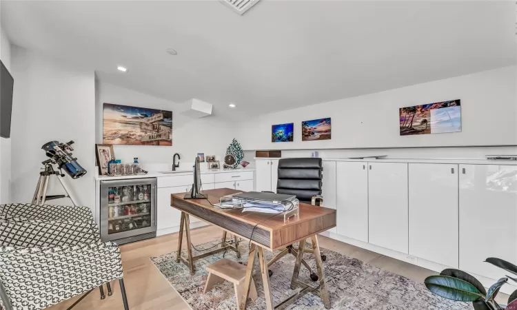 Office area with beverage cooler and light wood-type flooring