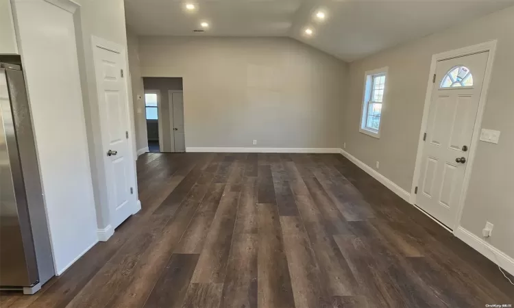 Foyer entrance featuring dark wood-type flooring and vaulted ceiling