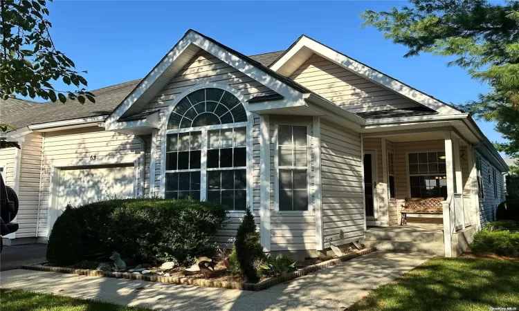 View of front of home featuring a garage, a front lawn, and covered porch