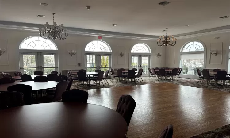 Event space featuring an inviting chandelier, dark wood-type flooring, and french doors