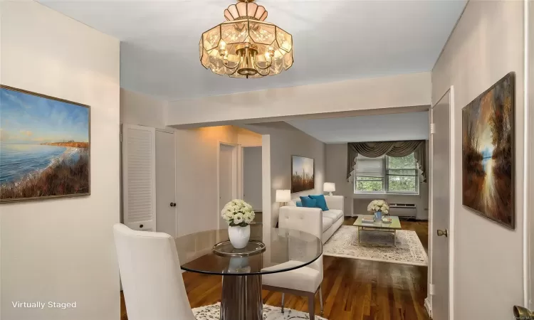 Dining space featuring hardwood / wood-style flooring, a notable chandelier, and a baseboard heating unit