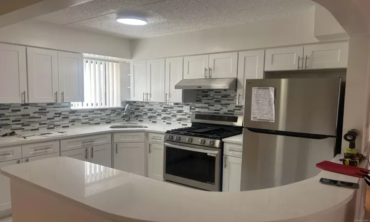 Kitchen featuring white cabinets, appliances with stainless steel finishes, tasteful backsplash, and sink