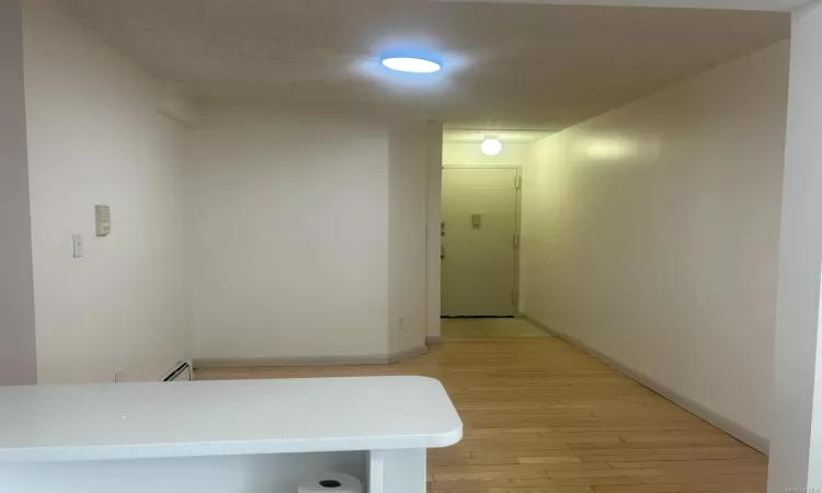 Hallway with light wood-type flooring and baseboard heating