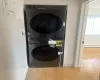 Laundry room with stacked washer and dryer, light hardwood / wood-style floors, and a baseboard radiator