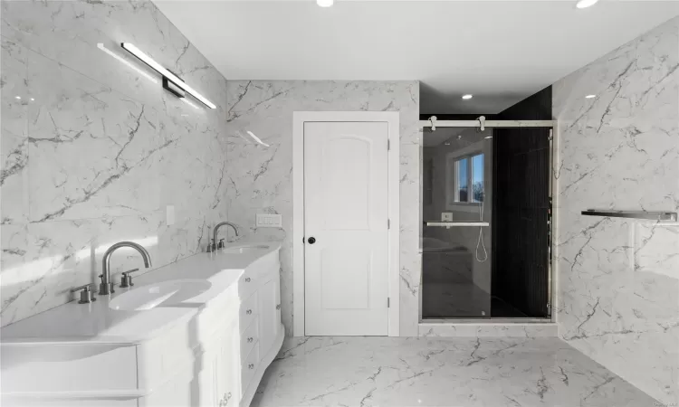 Bathroom featuring vanity, tile walls, and walk in shower