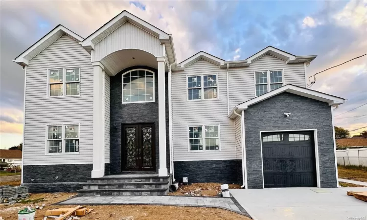 View of front of property featuring french doors, a garage, and a front lawn