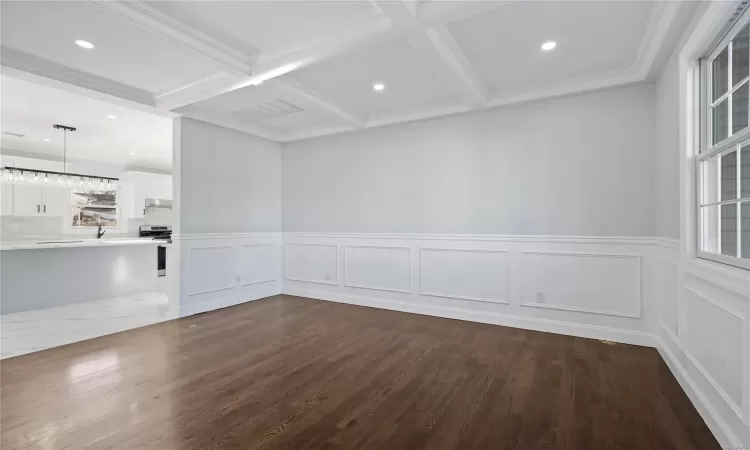 Unfurnished room with beam ceiling, dark hardwood / wood-style flooring, ornamental molding, and coffered ceiling