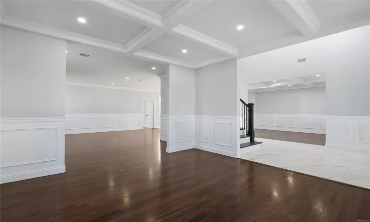 Empty room featuring beam ceiling, wood-type flooring, and crown molding