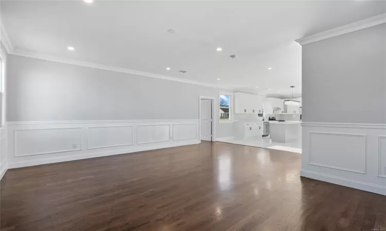 Unfurnished living room featuring dark hardwood / wood-style flooring and ornamental molding