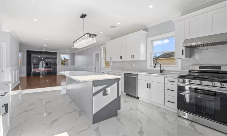 Kitchen featuring a center island, white cabinets, pendant lighting, and appliances with stainless steel finishes