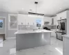 Kitchen with ornamental molding, stainless steel appliances, pendant lighting, white cabinets, and a center island