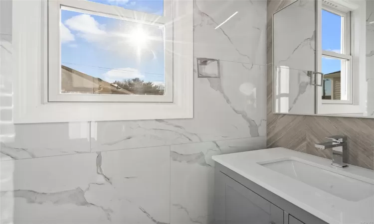 Bathroom with vanity and tile walls