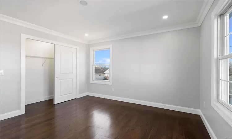 Unfurnished bedroom featuring crown molding, a closet, and dark hardwood / wood-style floors