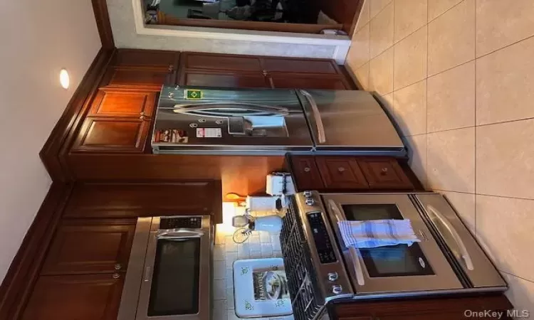 Kitchen featuring light tile patterned floors, stainless steel appliances, and ornamental molding