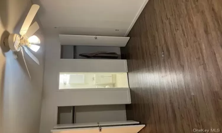 Unfurnished bedroom with connected bathroom, ceiling fan, multiple closets, and dark hardwood / wood-style floors