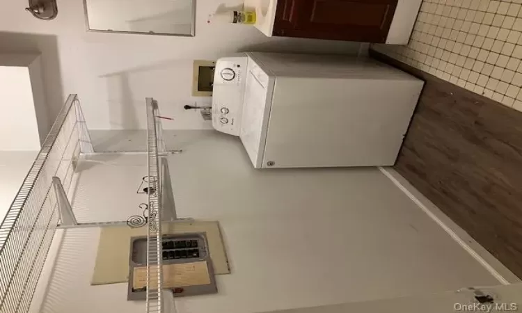 Washroom featuring washer / dryer, electric panel, and light hardwood / wood-style flooring