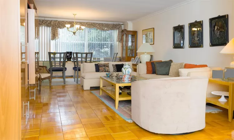 Living room featuring parquet flooring, crown molding, and an inviting chandelier