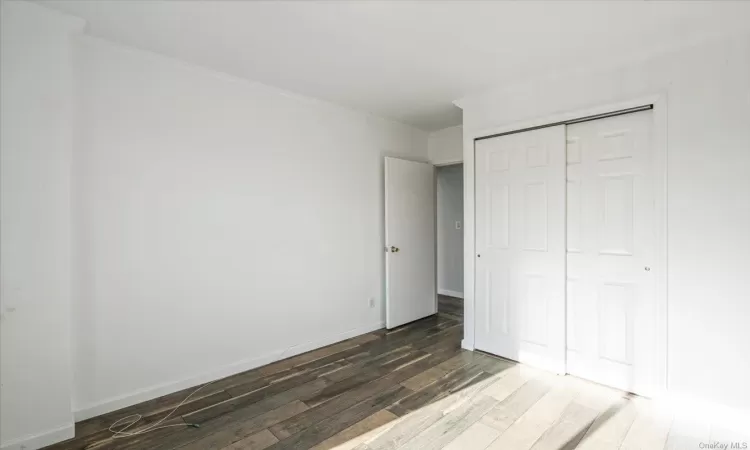 Unfurnished bedroom with dark hardwood / wood-style floors, a closet, and crown molding