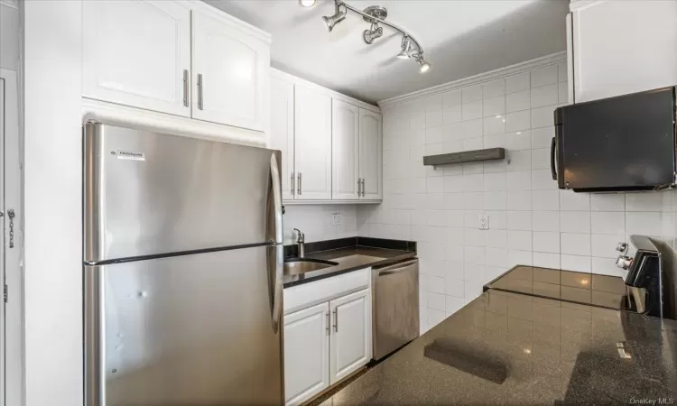 Kitchen featuring white cabinets, crown molding, sink, and appliances with stainless steel finishes