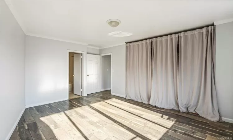 Empty room featuring dark hardwood / wood-style flooring and ornamental molding