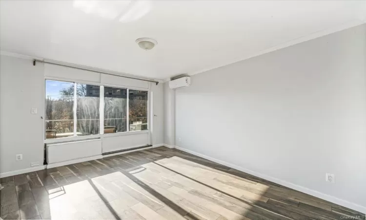 Spare room featuring dark hardwood / wood-style flooring, a wall mounted air conditioner, and ornamental molding