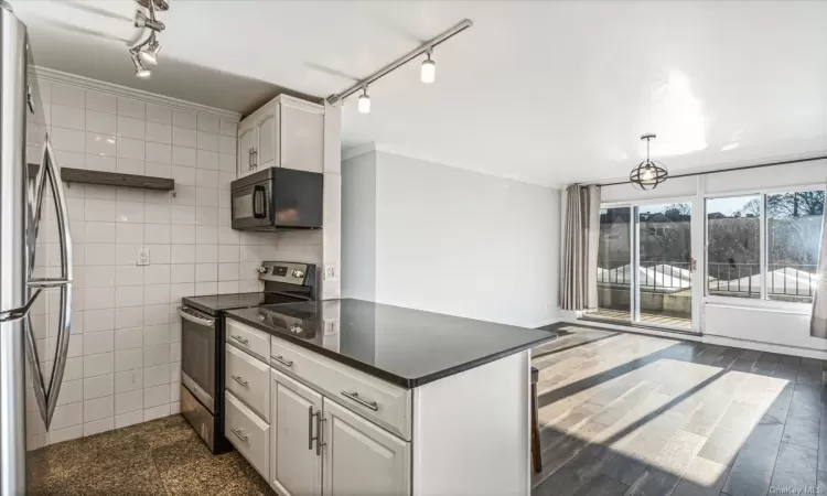 Kitchen featuring dark hardwood / wood-style floors, white cabinetry, stainless steel appliances, and tile walls