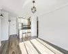 Kitchen with stainless steel fridge, white cabinetry, hardwood / wood-style floors, and crown molding