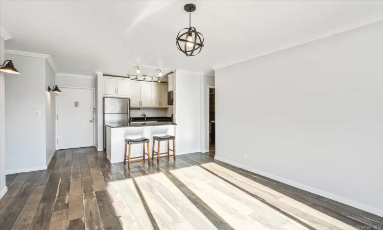 Kitchen with stainless steel fridge, white cabinetry, hardwood / wood-style floors, and crown molding