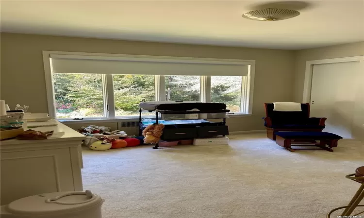 Empty room featuring light parquet floors, a baseboard radiator, and a notable chandelier