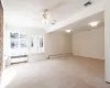 Spare room featuring light carpet, a brick fireplace, radiator, ceiling fan, and a baseboard radiator