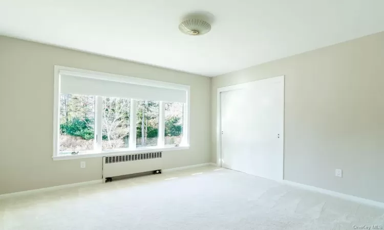 Carpeted spare room featuring radiator heating unit