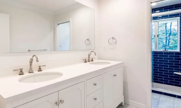 Bathroom featuring tiled shower, vanity, and ornamental molding