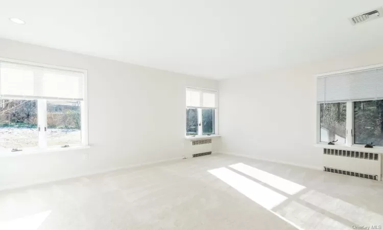 Empty room with light colored carpet and radiator