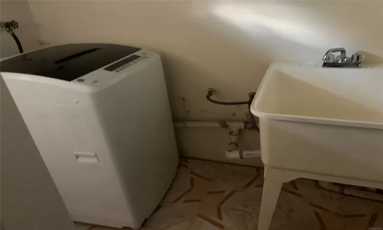 Laundry area with washer / dryer, light tile patterned floors, and sink