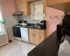 Kitchen featuring white appliances, radiator, sink, light tile patterned floors, and range hood