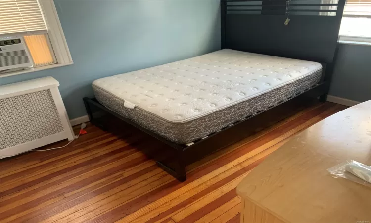 Bedroom featuring dark hardwood / wood-style flooring, cooling unit, and radiator heating unit