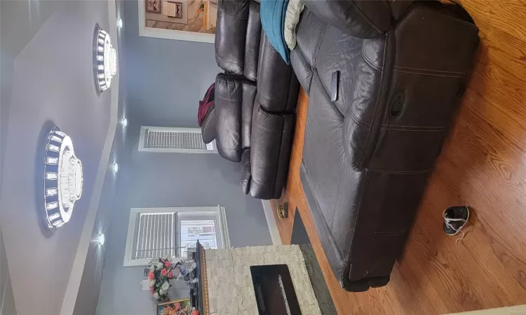 Living room with a stone fireplace, hardwood / wood-style floors, and lofted ceiling