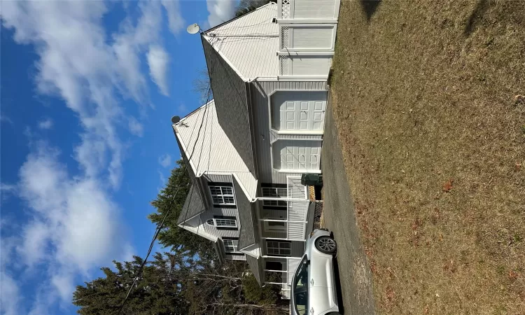 View of front of house with covered porch, a garage, and a front lawn