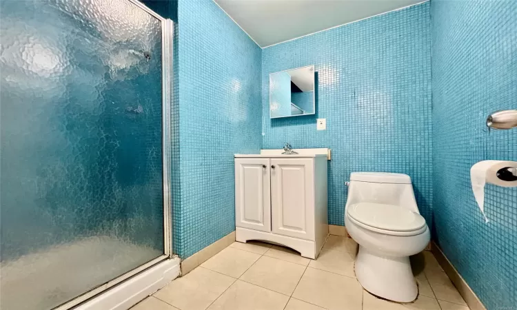 Bathroom with tile patterned flooring, vanity, toilet, and walk in shower