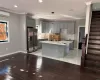 Kitchen with gray cabinetry, stainless steel fridge, crown molding, and an island with sink