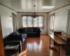 Living room with a chandelier, light wood-type flooring, crown molding, and a skylight