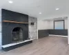 living room\ Dining room featuring a fireplace, wood-type flooring, and a baseboard heating unit