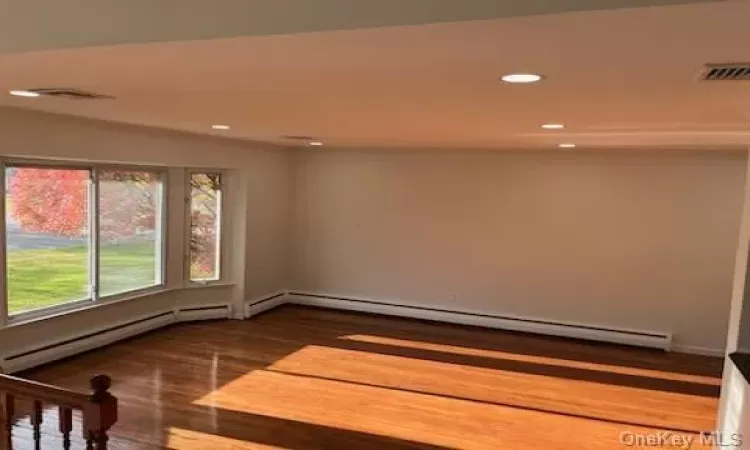 Unfurnished room with dark hardwood / wood-style flooring and a baseboard heating unit