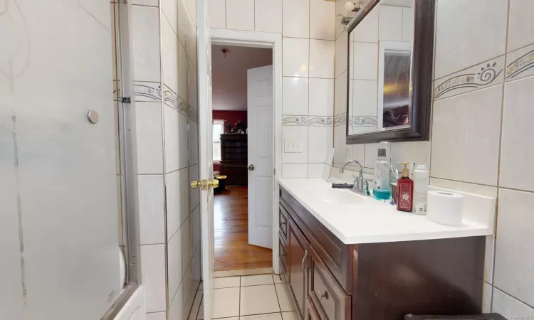 Bathroom featuring tile patterned floors, vanity, and tile walls