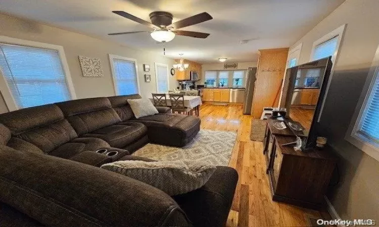 Kitchen with light brown cabinetry, ceiling fan with notable chandelier, stainless steel appliances, pendant lighting, and light hardwood / wood-style floors